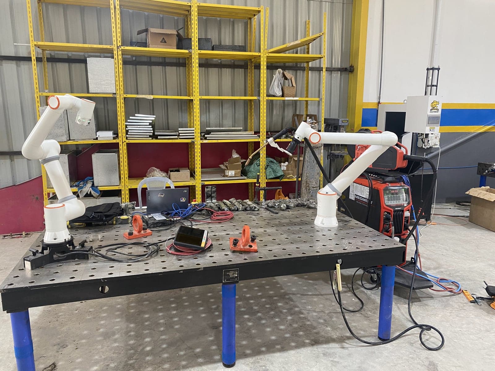Two Fairino robot arms at the welding table in the Cyber Robot workshop